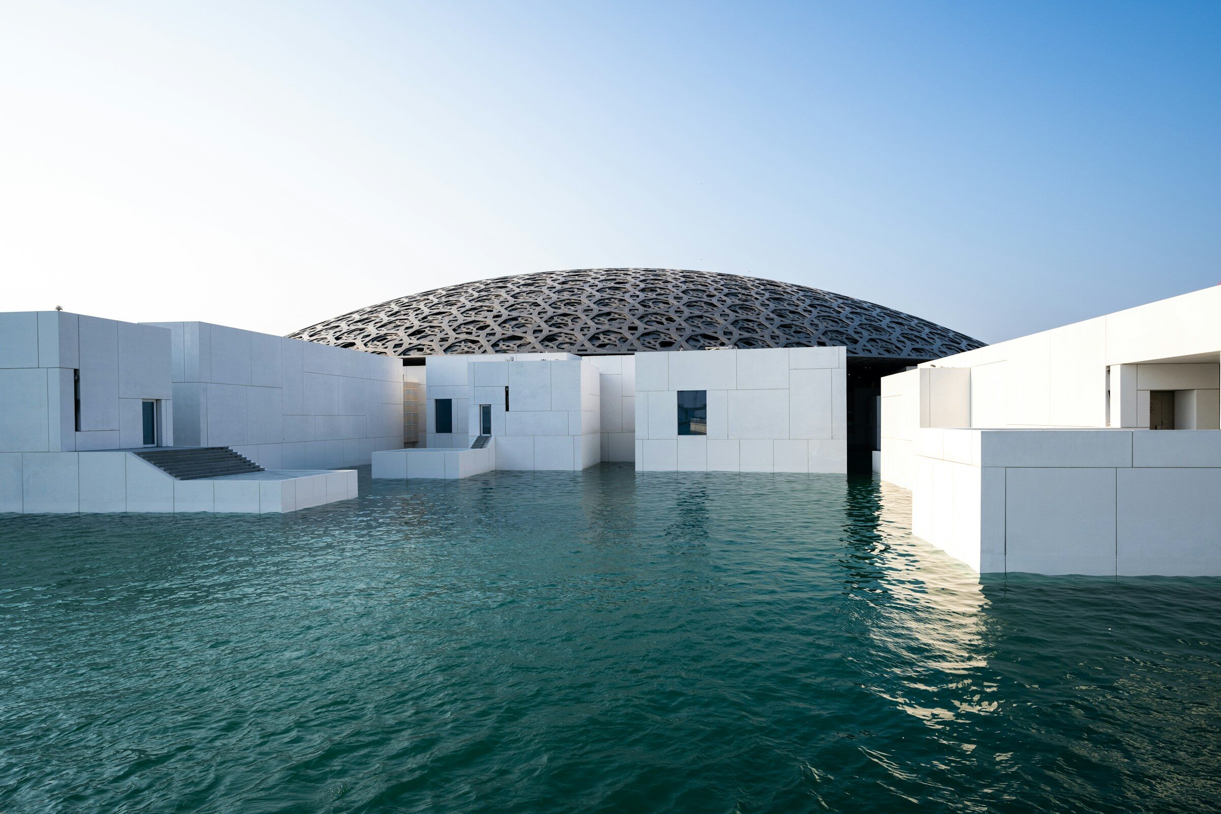 The modern domed roof of the Louvre Abu Dhabi over water