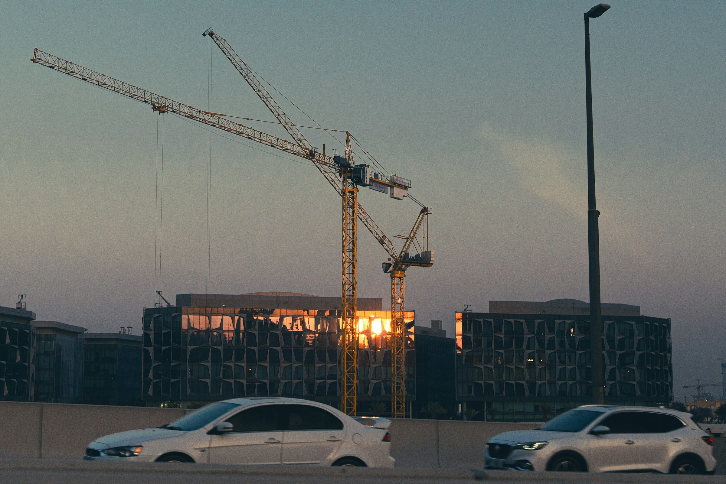 Construction cranes and buildings at sunset