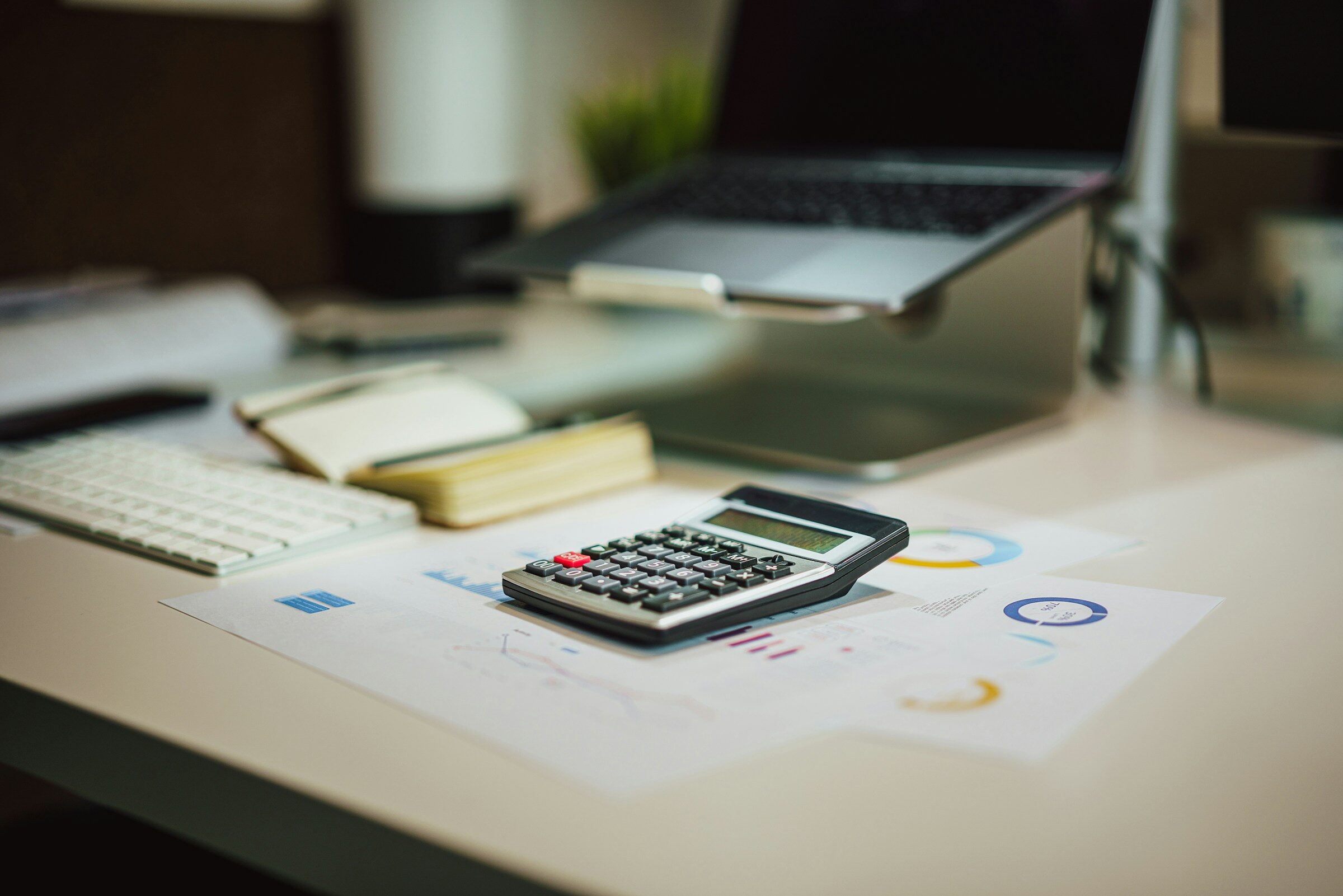 A calculator on a desk beside a laptop