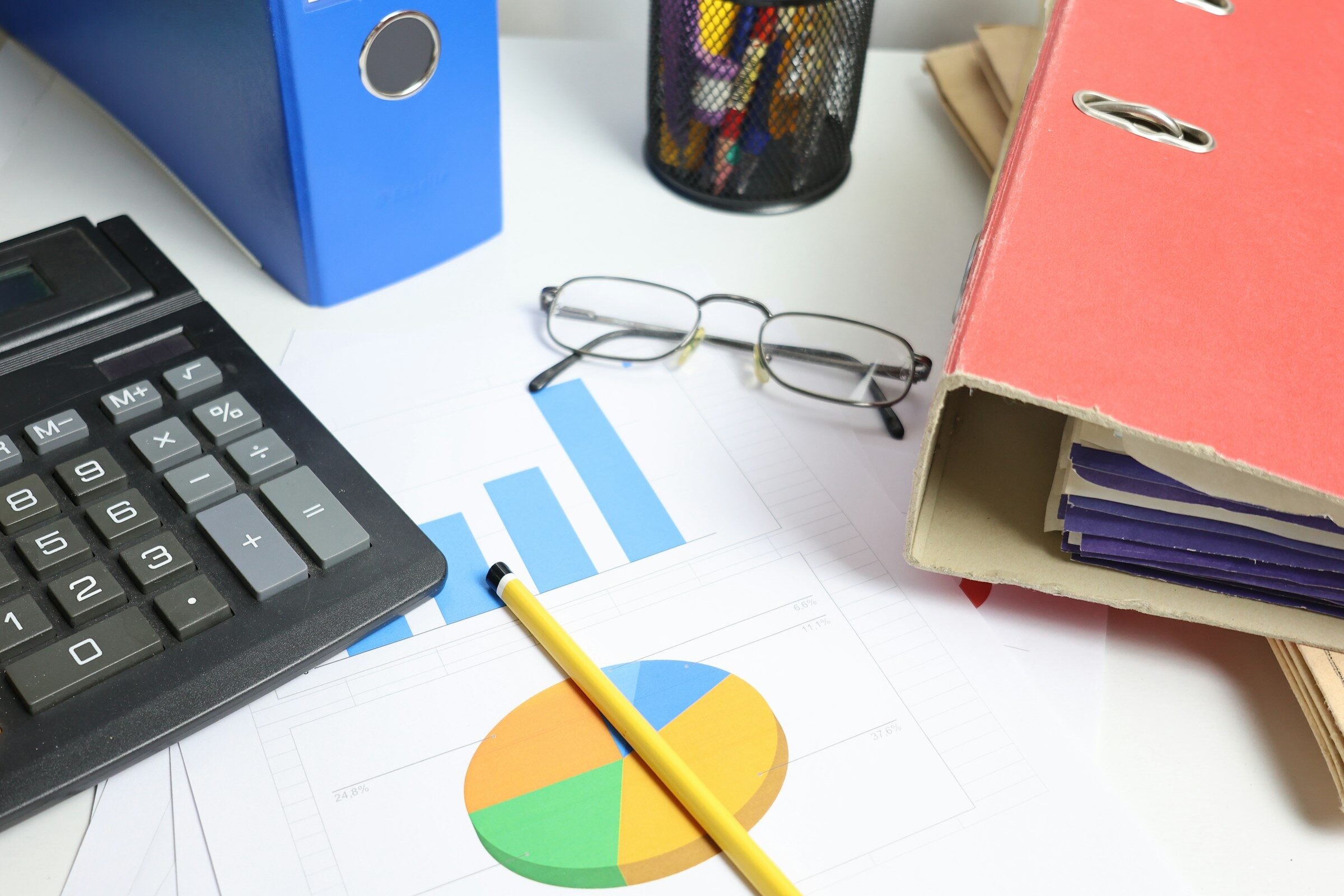 A desk with a calculator, printed charts and binders