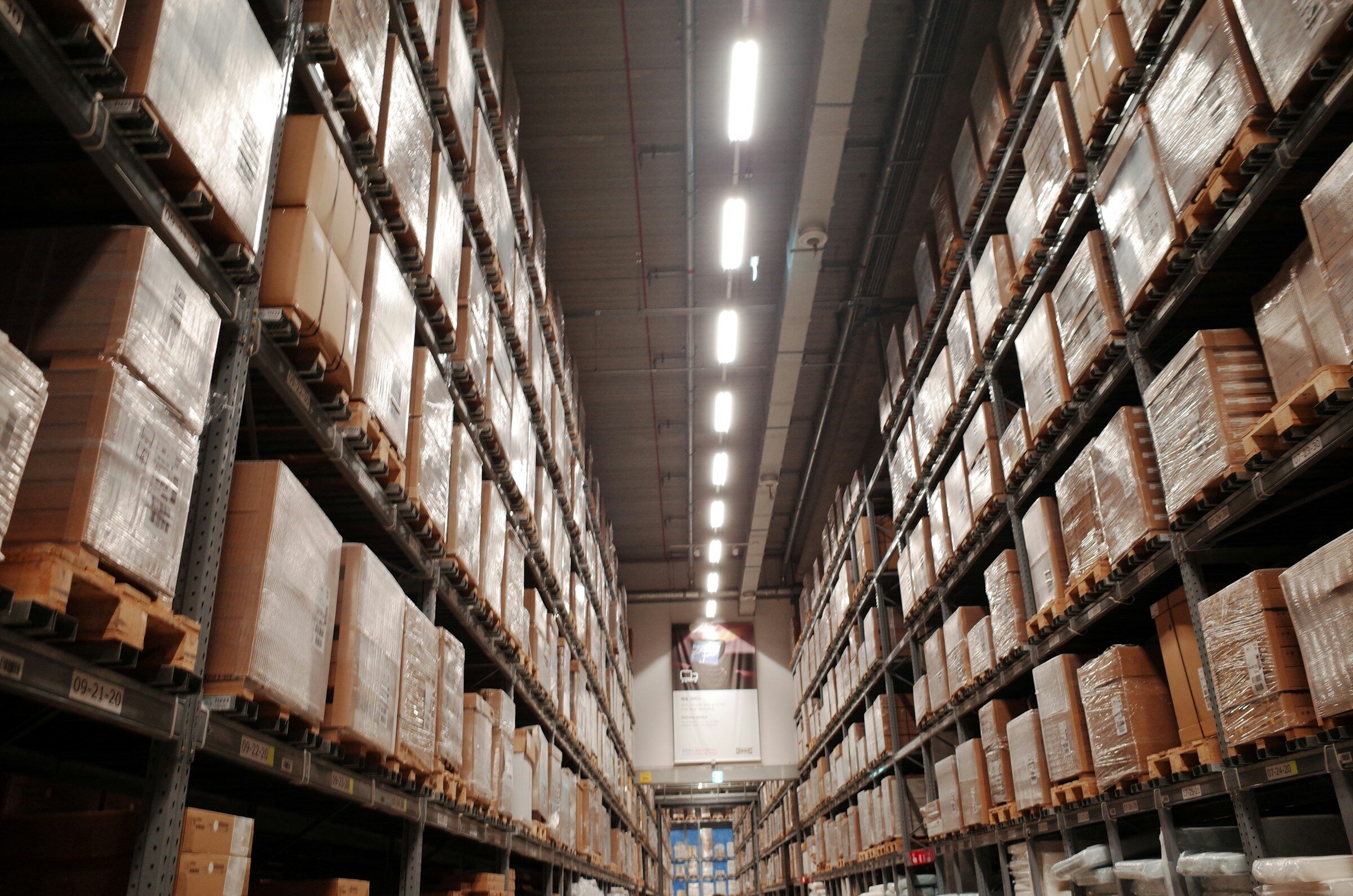 A wide warehouse aisle stacked to the roof with boxed stock