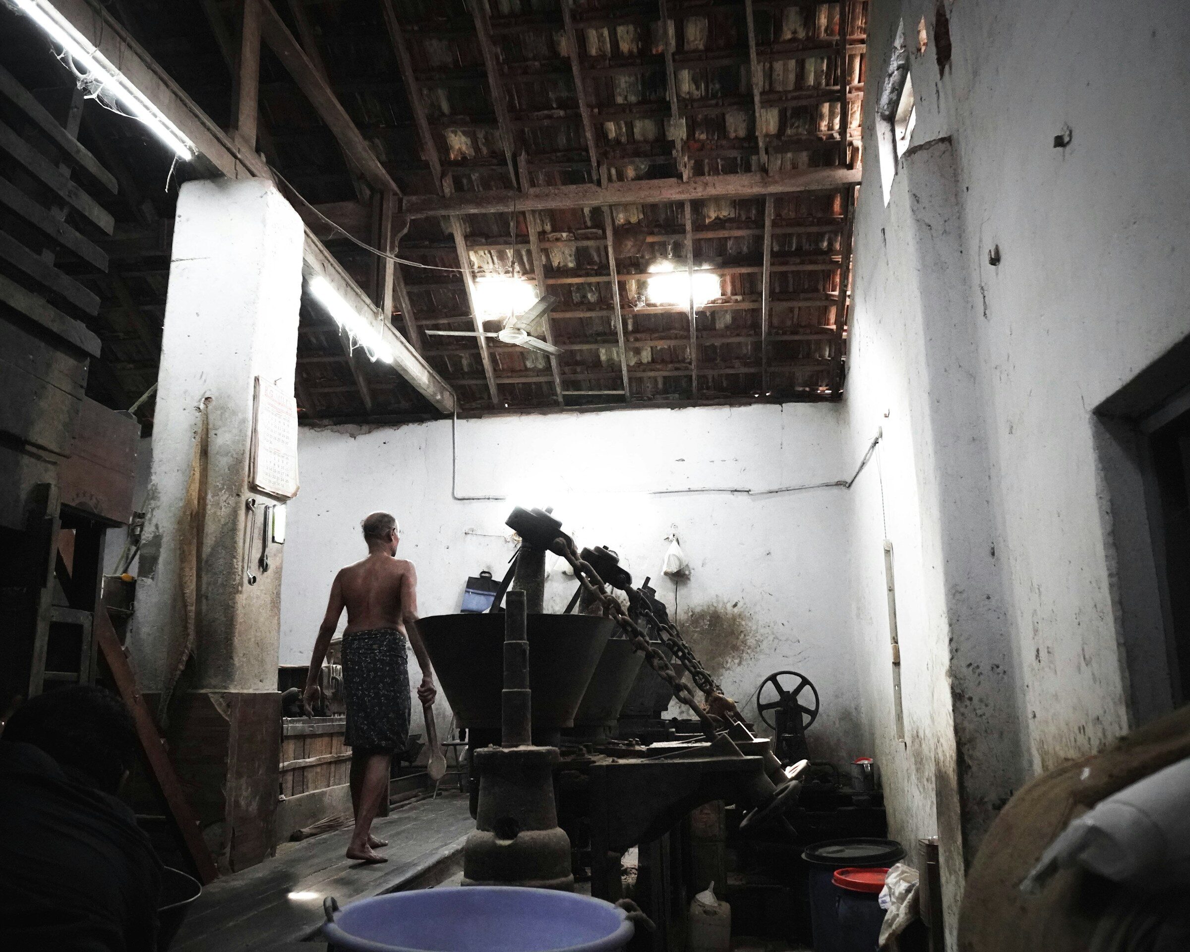 A man standing beside a machine in a small factory