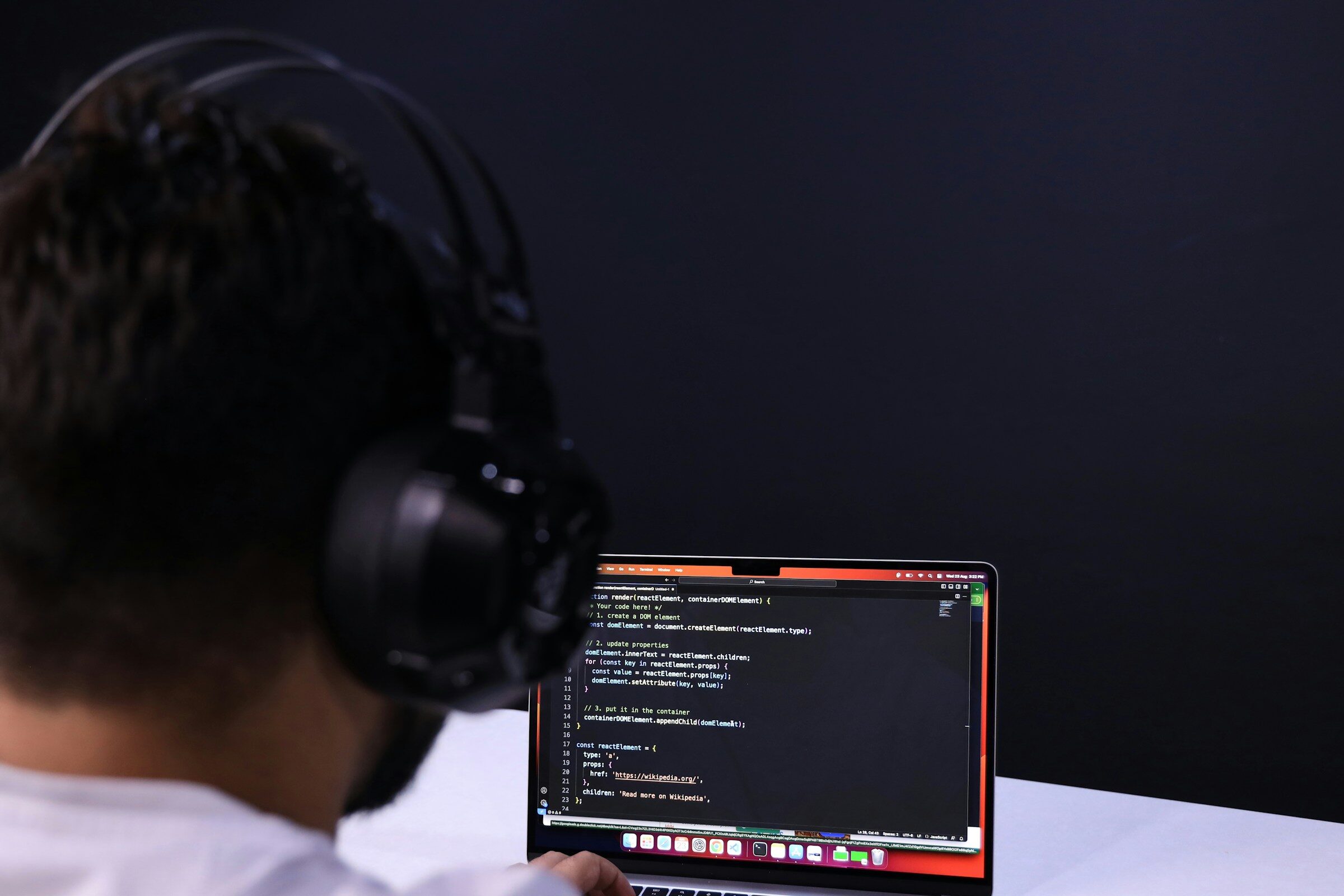 A man wearing headphones working at a laptop