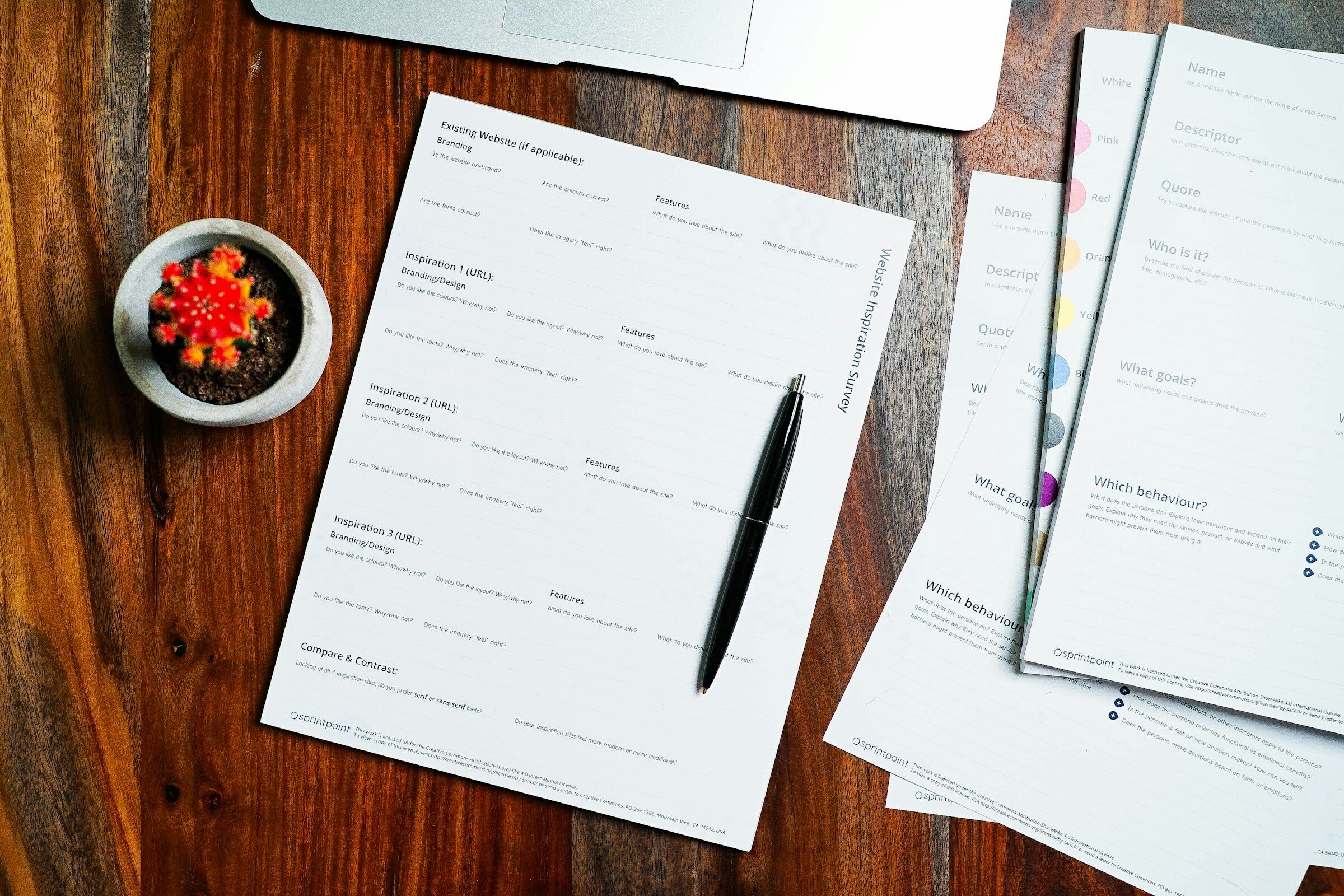 A wooden table with papers and a pen