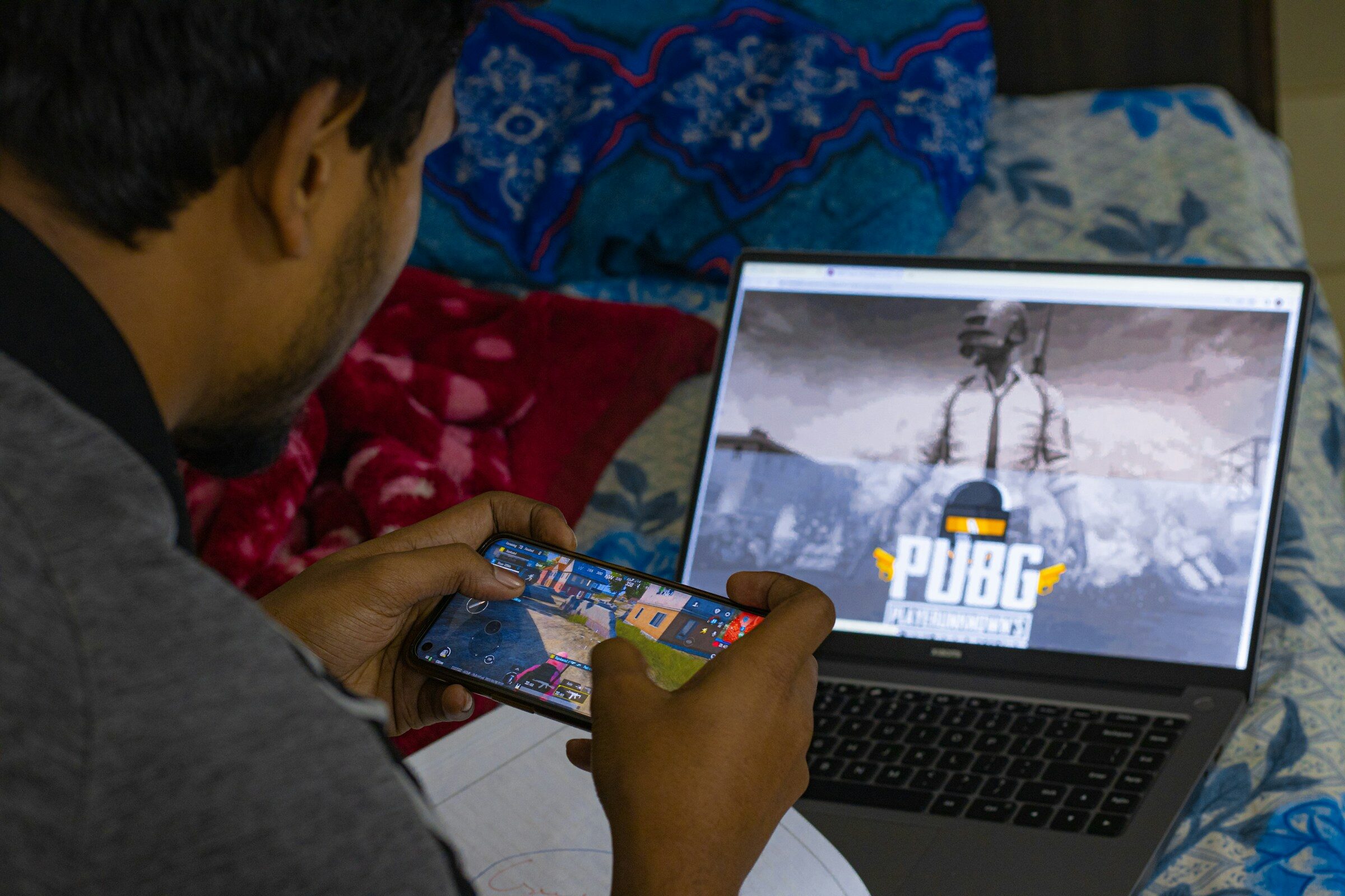 A person using a phone beside a laptop screen