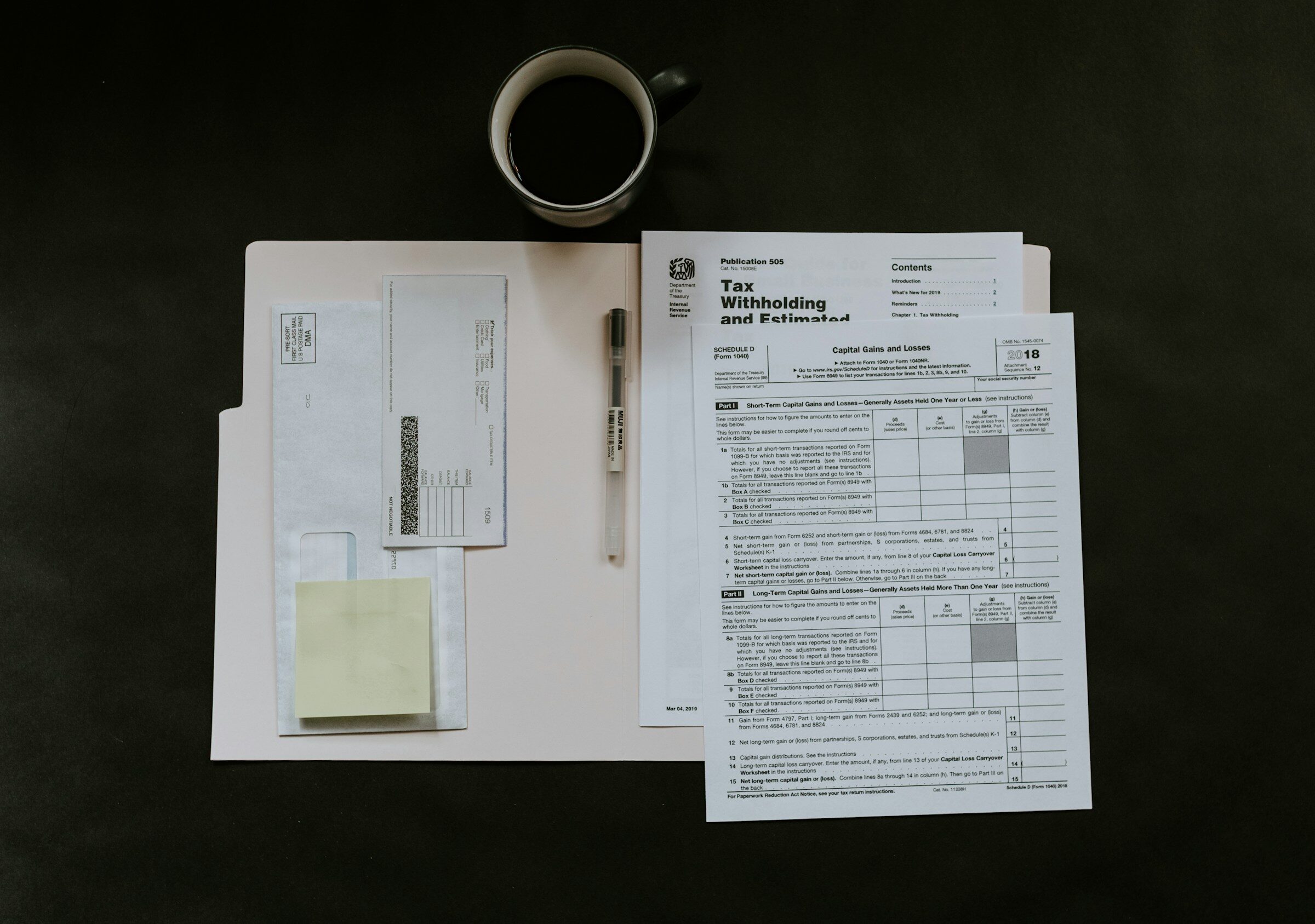 Tax forms, a pen and a mug on a dark desk