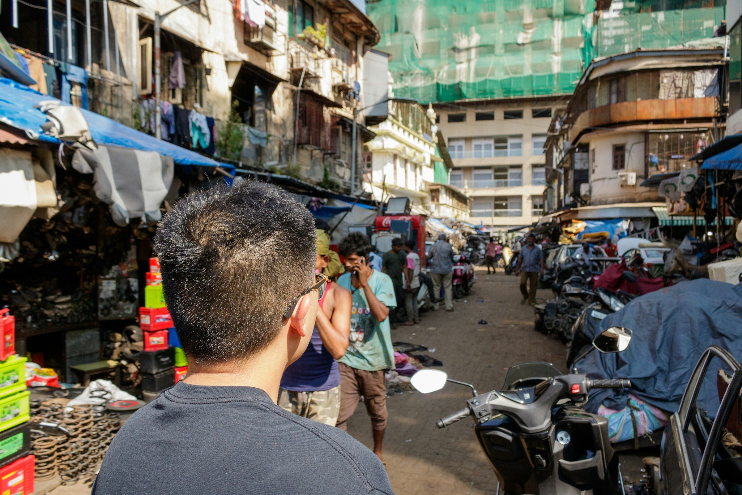 A crowded Mumbai wholesale street lined with stalls and parked motorcycles