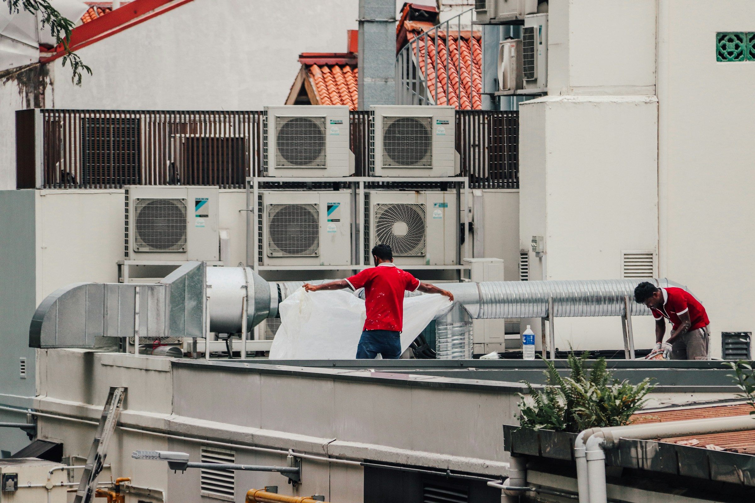 Two technicians working on rooftop air-conditioning units
