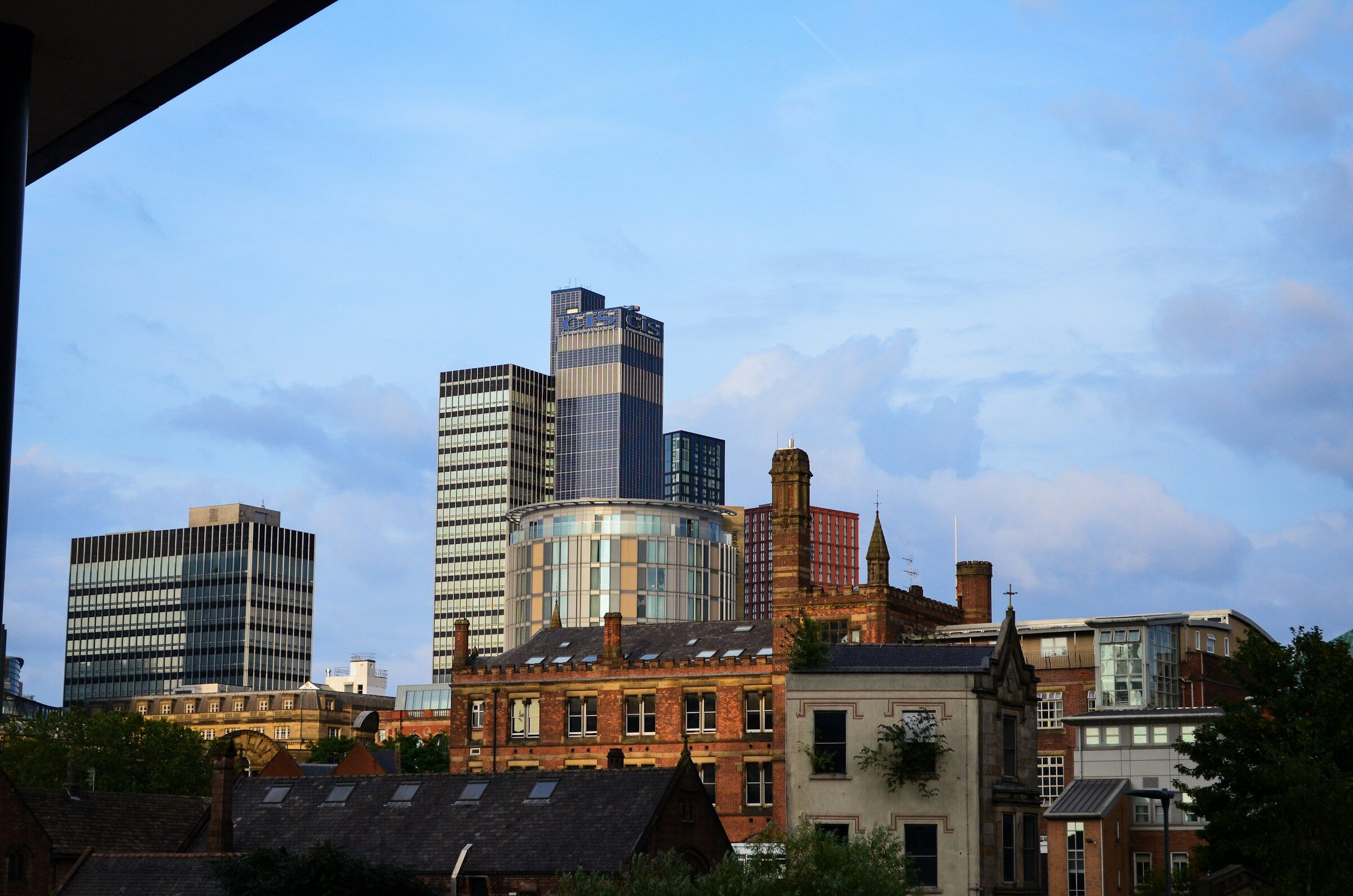 Modern towers rising behind historic red-brick warehouses in Manchester