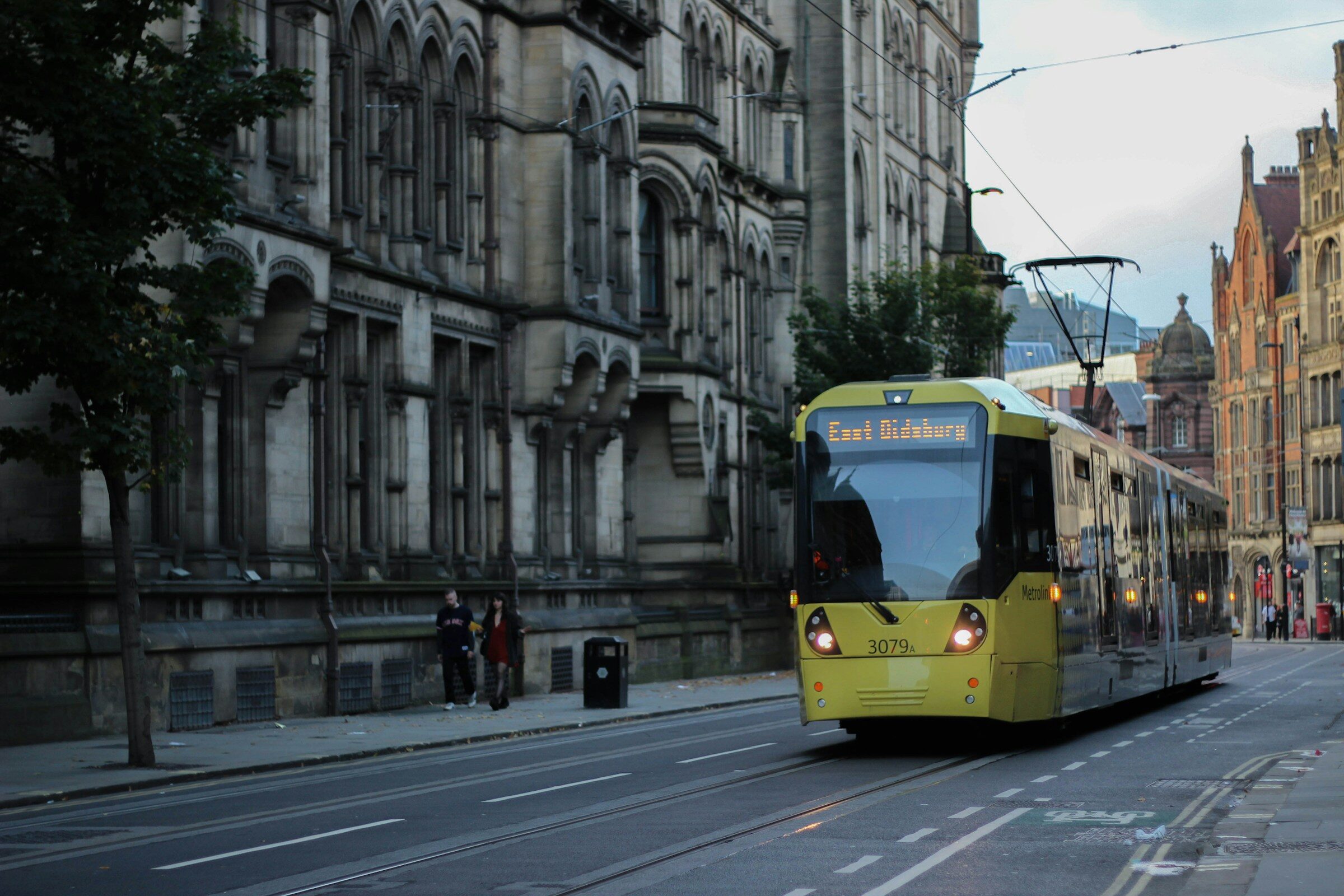 A yellow Metrolink tram on a Manchester street
