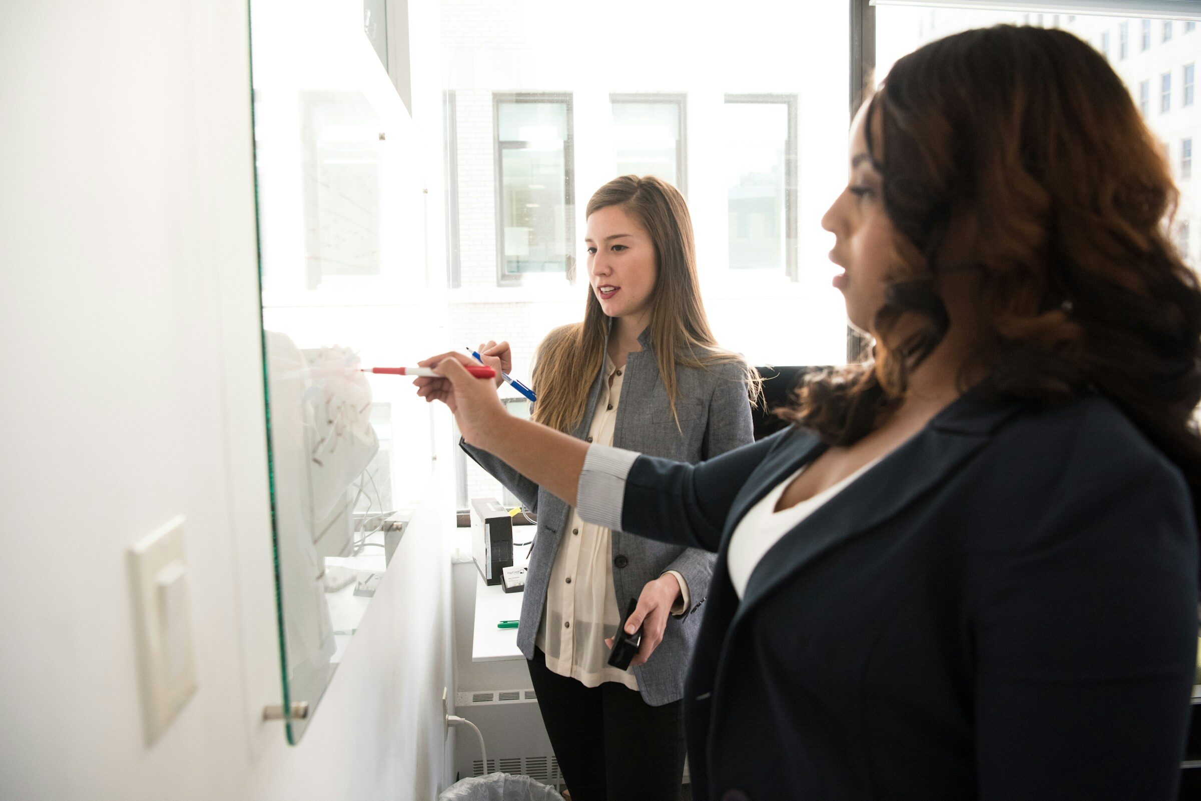 Colleagues mapping a process on a glass panel