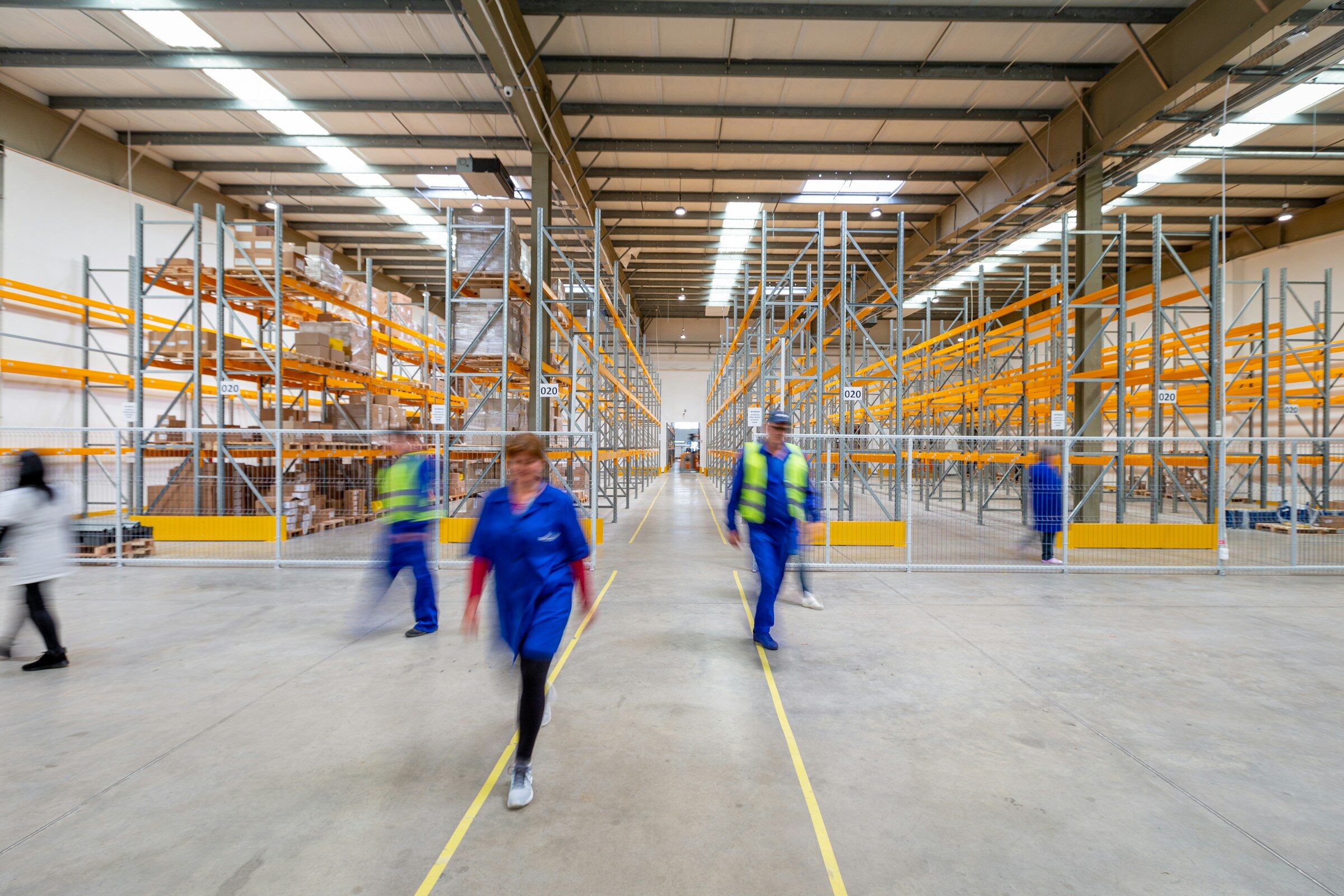 Staff walking down an aisle in a busy warehouse