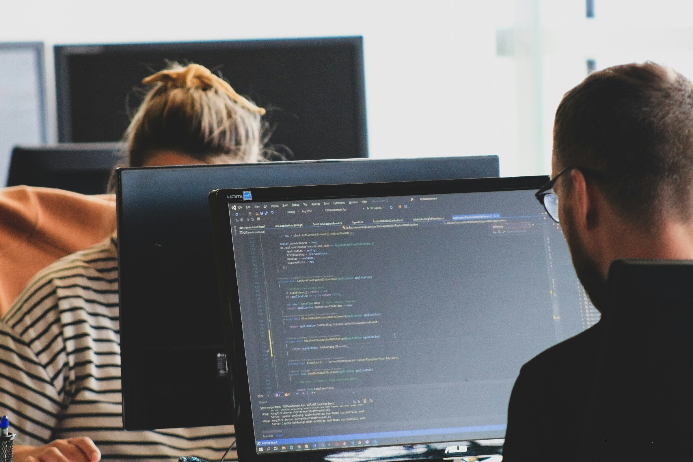 Two developers reviewing a build at their monitors