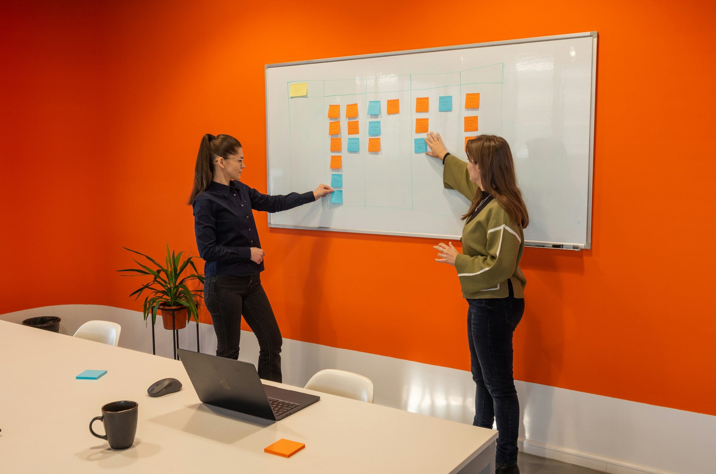 Two people working through a process diagram at a whiteboard