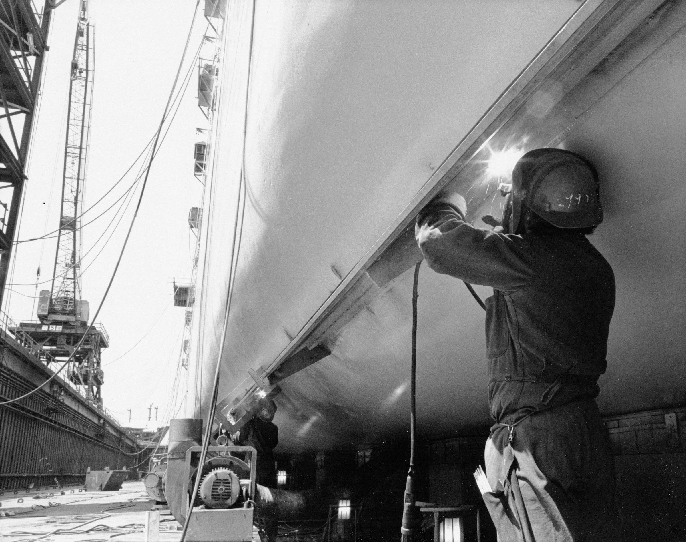 A welder working on the hull of a ship in dry dock