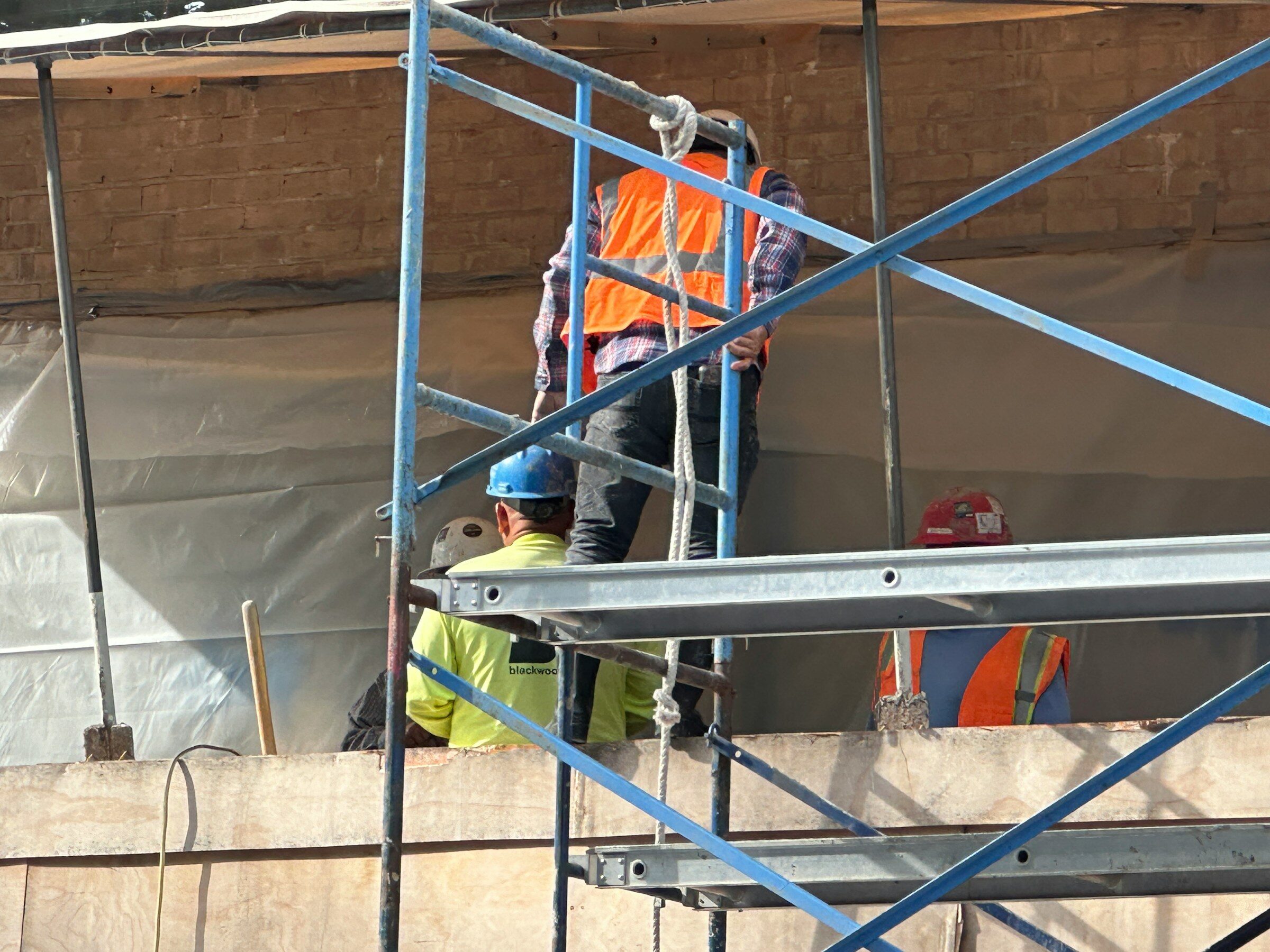 Two workers on scaffolding partway up a building